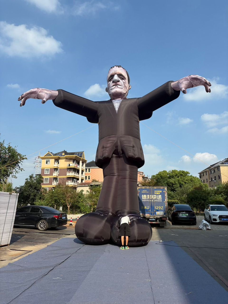 Towering Frankenstein inflatable with a person beside its feet for scale