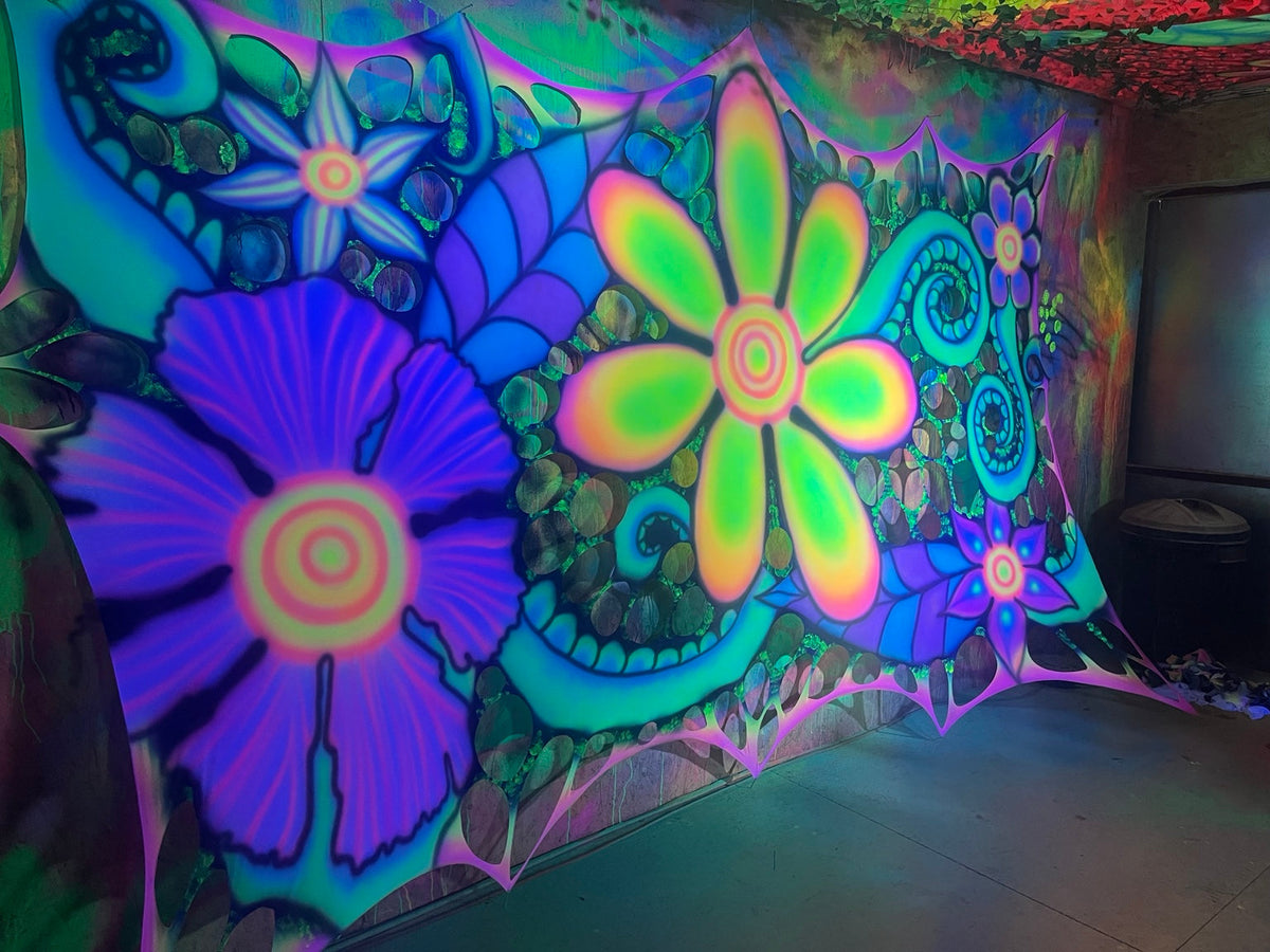 Psychedelic floral UV stretch decor installed across a wall under blacklight