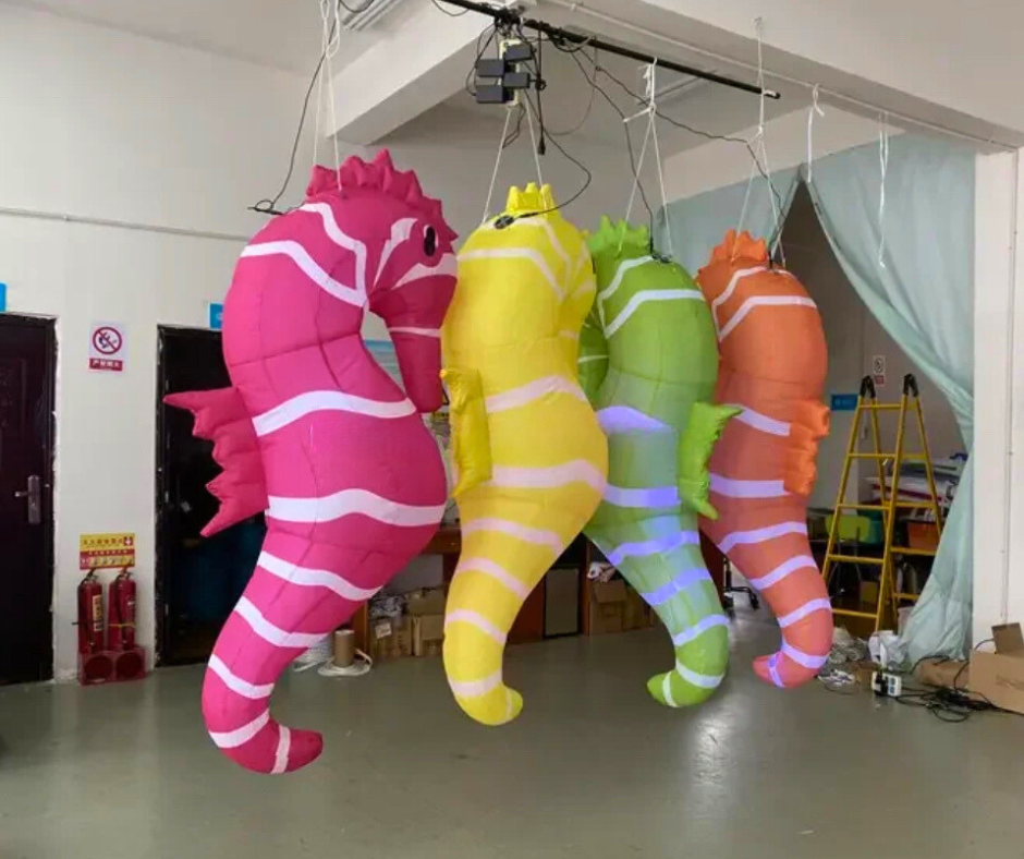 Four colorful inflatable seahorses hanging from the ceiling in a room.