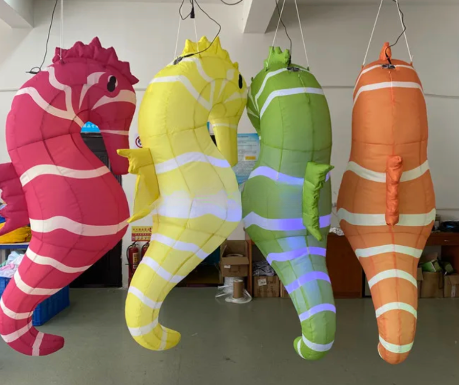 Four inflatable seahorse toys in pink, yellow, green, and orange hanging in a room.
