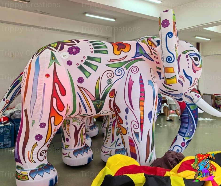 Colorful inflatable elephant model in a room with people and furniture.