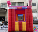 Colorful inflatable bounce house with cotton candy-themed roof in an urban setting.
