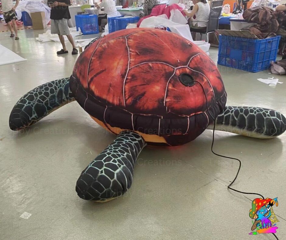 Inflatable sea turtle on a floor with people and blue crates in the background