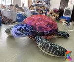 Colorful inflatable turtle toy on a floor with people and furniture in the background