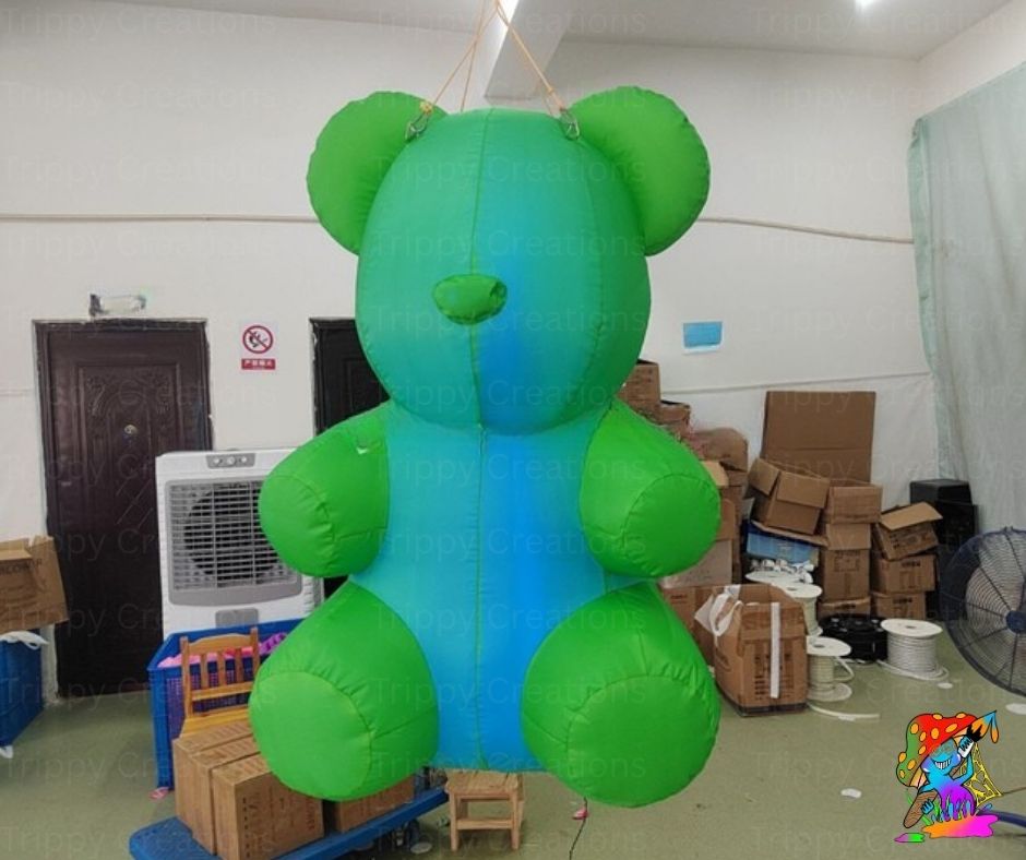 Inflatable green teddy bear in a warehouse setting with boxes and equipment.