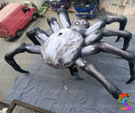 Giant inflatable black spider hanging from ceiling with invisible thread, creating a floating illusion