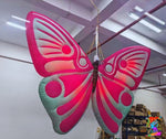Large inflatable butterfly with pink and green wings hanging indoors.