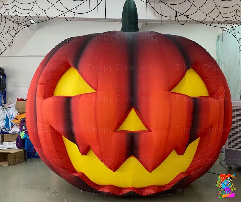 Inflatable pumpkin decoration with a jack-o'-lantern face, predominantly red and orange with black details.