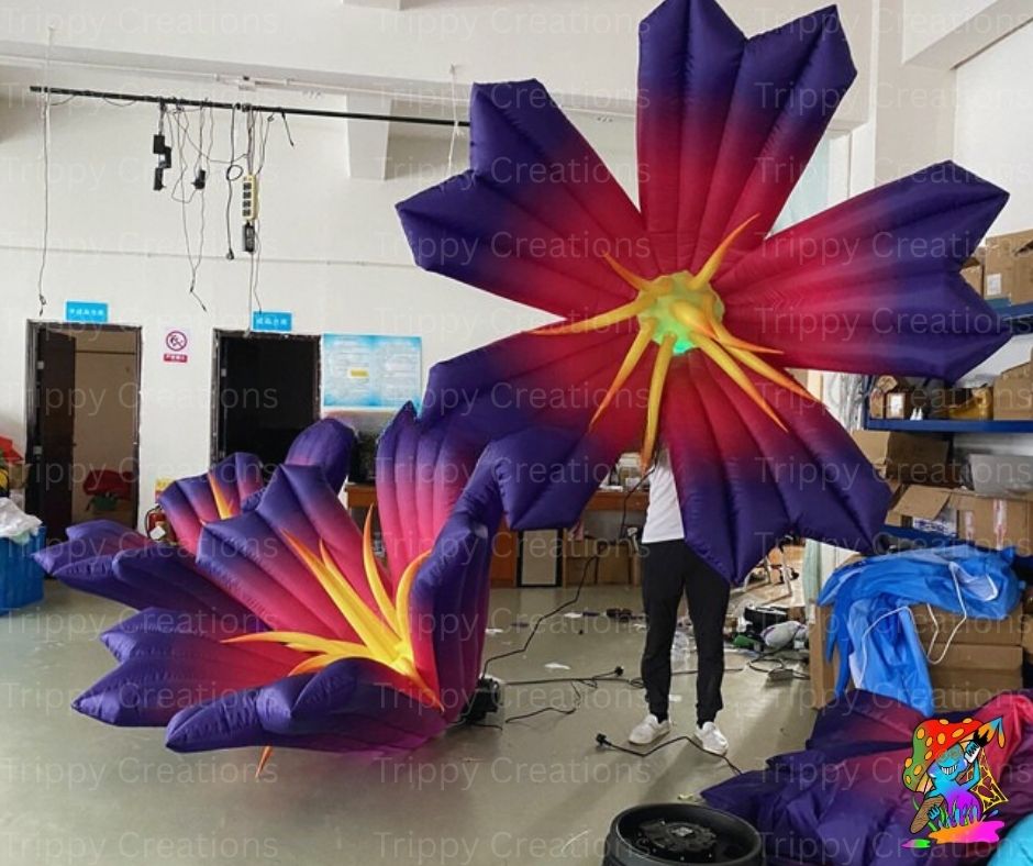Inflatable flower decorations in a warehouse setting with 'Trippy Creations' branding.