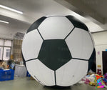 Large inflatable soccer ball in an indoor setting with people and furniture.