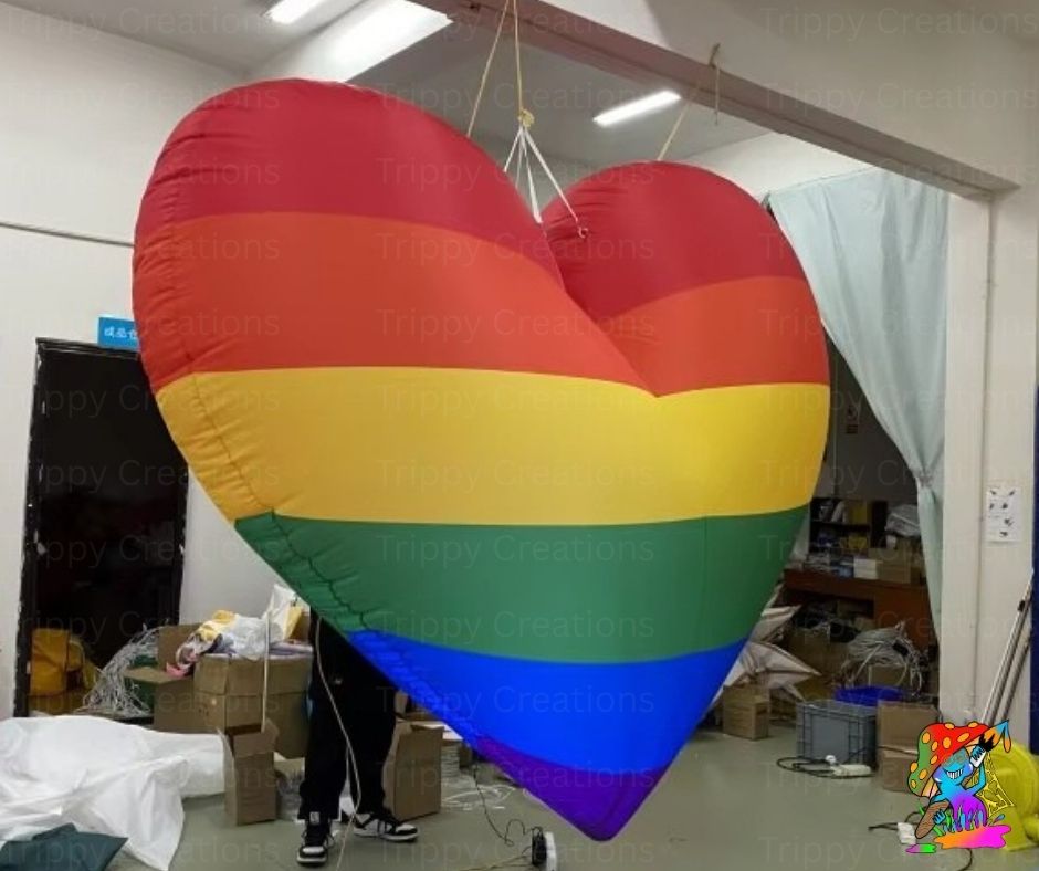 Large rainbow-colored heart-shaped balloon in a storage or warehouse setting.