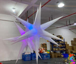 Inflatable star-shaped structure with colorful lights in a warehouse setting.