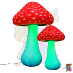 Two inflatable mushroom-shaped floor lamps with red caps speckled with white dots and glowing green to blue stems, shown on a white background with a power cord.