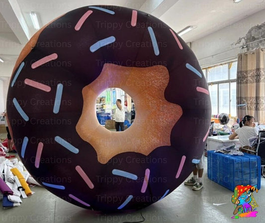 Large inflatable donut with chocolate glaze and sprinkles in an indoor setting.