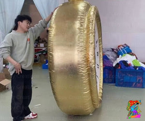 Person holding a large gold inflatable object in an indoor setting with various items and furniture.