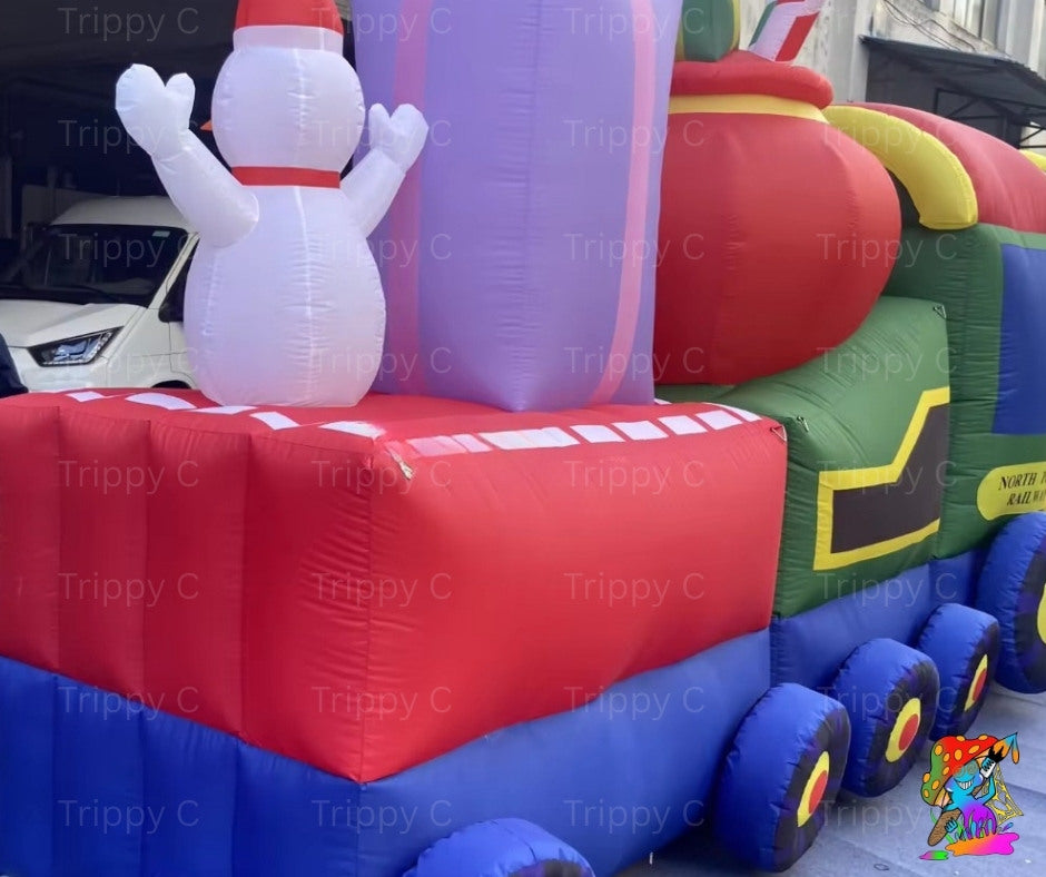 Inflatable Christmas train with snowman on top, featuring red, blue, green, and purple colors.