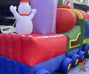 Inflatable Christmas train with snowman on top, featuring red, blue, green, and purple colors.
