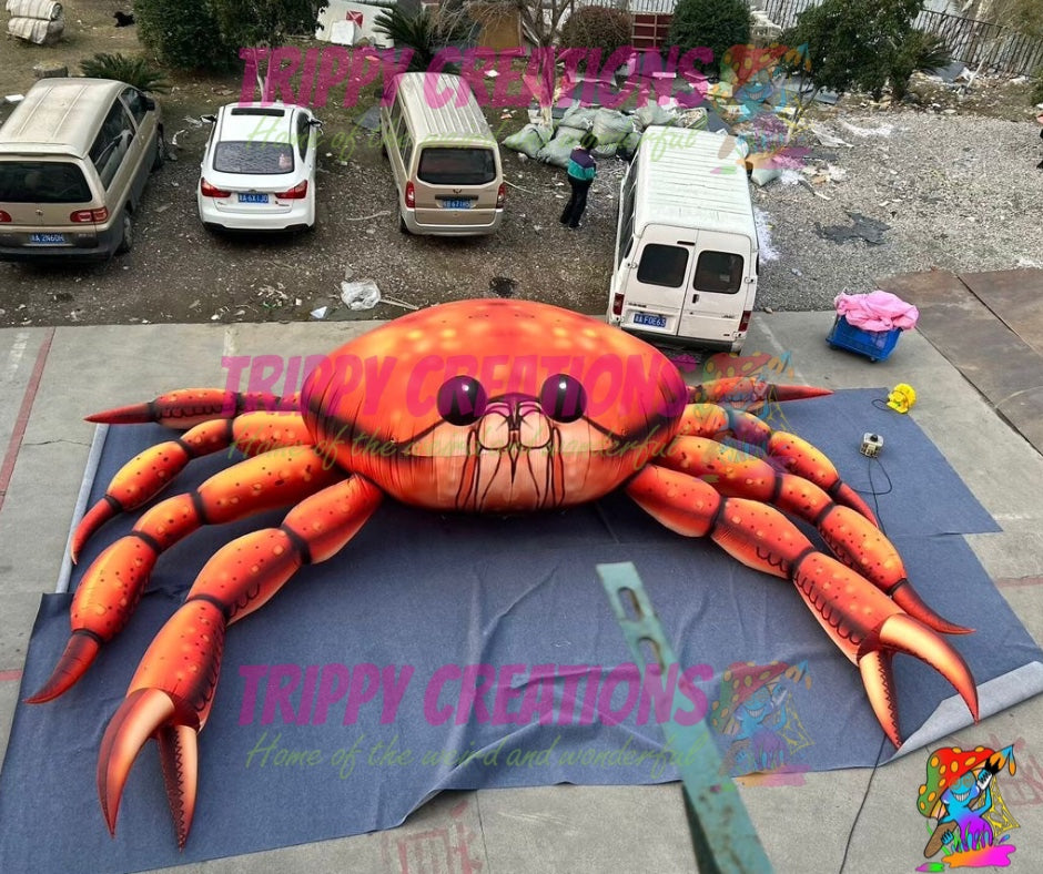 Large inflatable crab on a blue tarp with 'Trippy Creations' branding in an outdoor setting.