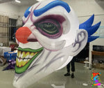 Close-up of creepy clown inflatable with sinister smile and glowing eyes, ideal for haunted house decor.