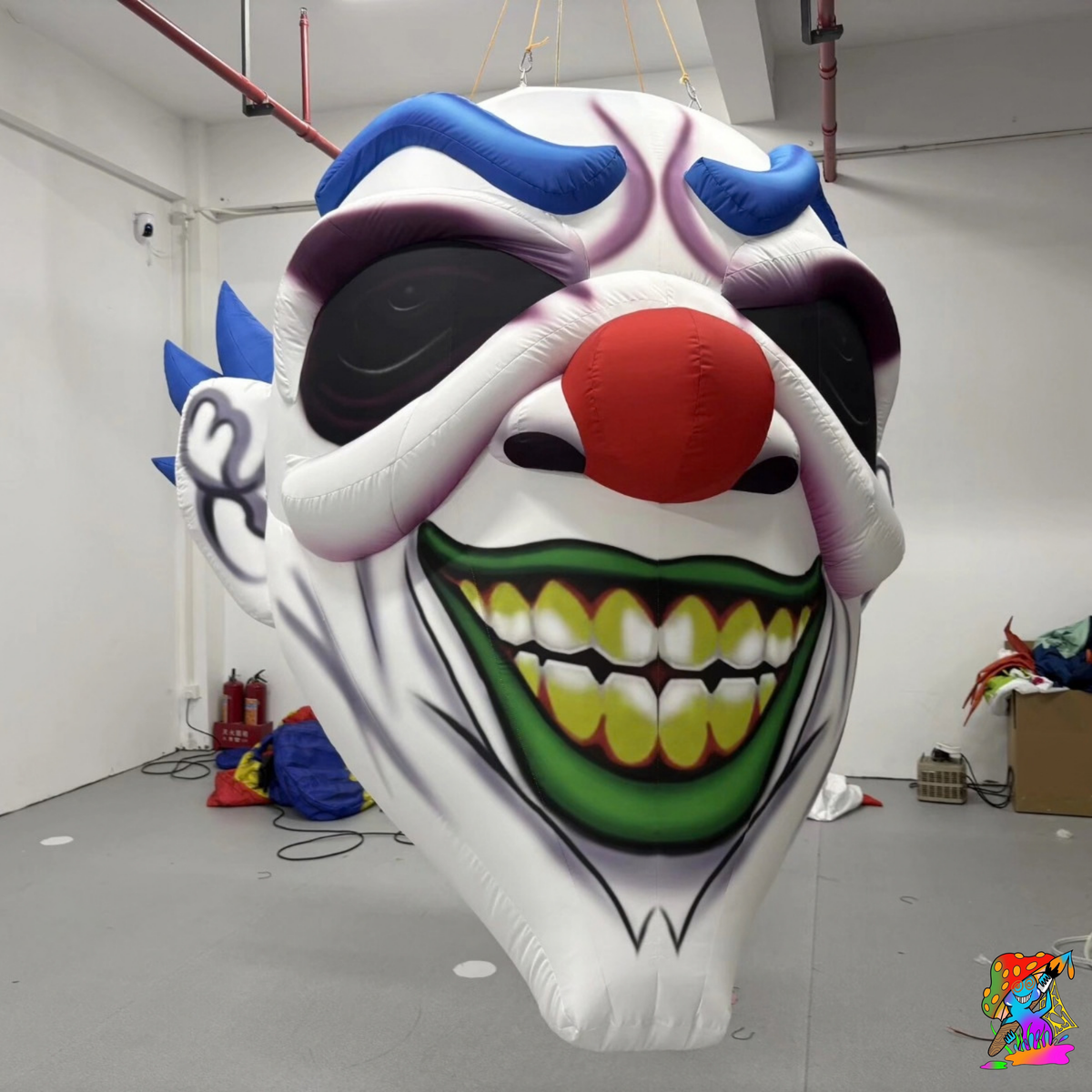Giant hanging inflatable clown head with blue hair, red nose and a sinister grin for Halloween event décor.