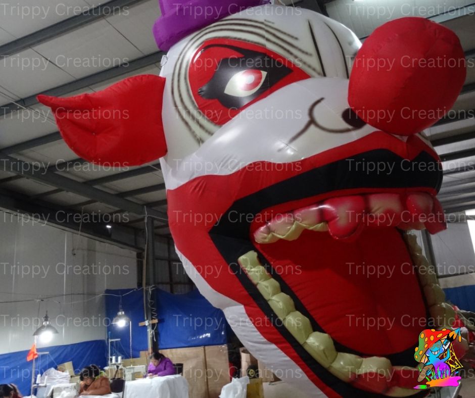 Two giant clown face decorations inflated and hanging above a circus-style event entrance