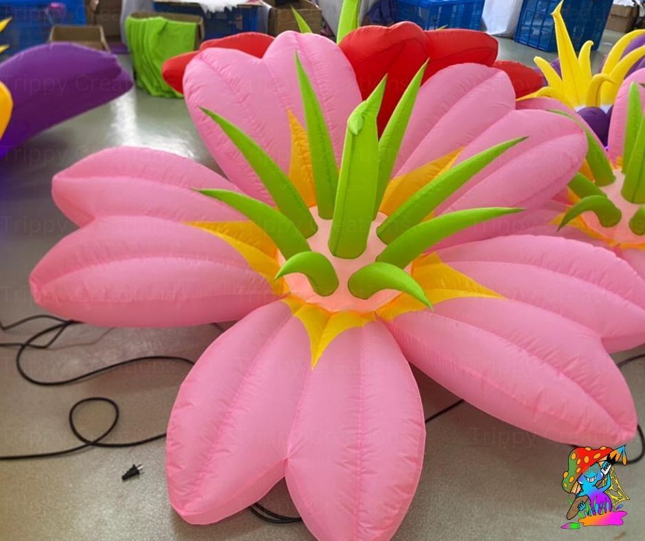 Trippy Creations giant pink inflatable flower decoration with green leaves and yellow accents, ideal for whimsical events.