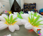 Trippy Creations giant white inflatable flower decoration with green leaves and yellow center, lit from within.
