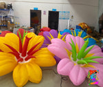 Trippy Creations giant inflatable flowers in yellow, pink, purple, and blue with red and green accents. Whimsical decor for parties.