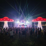 Trippy Creations giant red and white inflatable mushroom party decoration with LED lights at an outdoor night event.