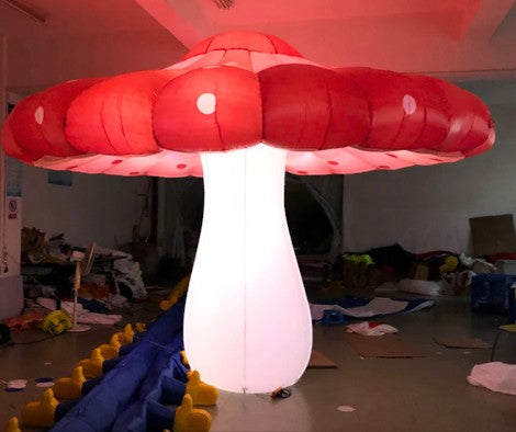 Trippy Creations giant inflatable mushroom decoration, red cap with white spots, illuminated white stem, perfect for parties.
