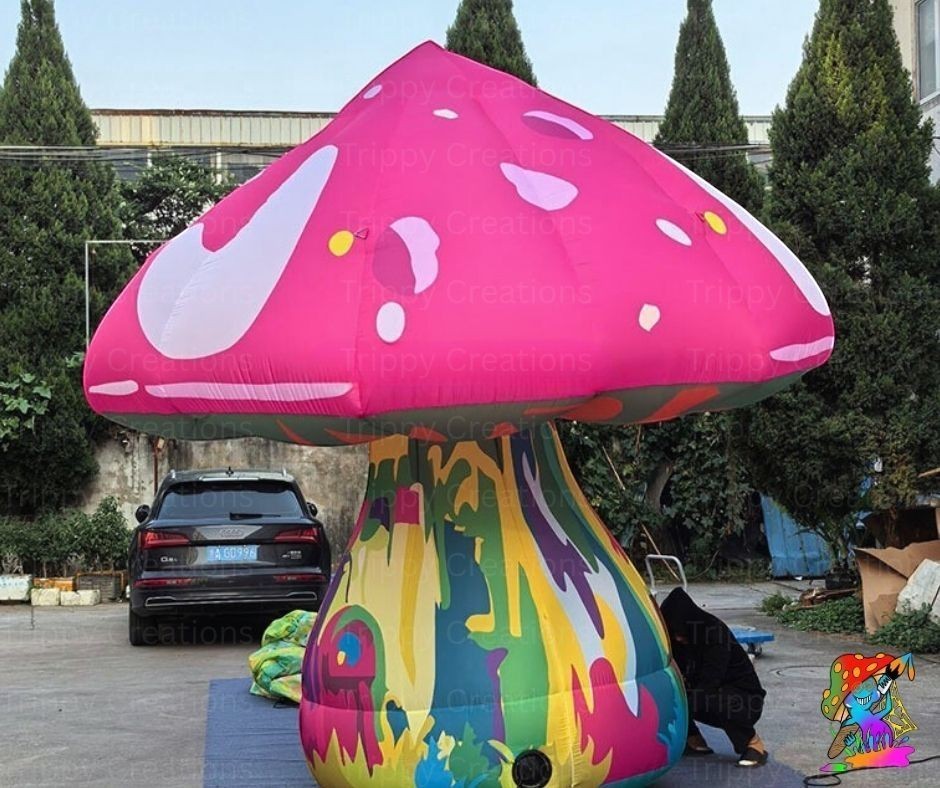 Trippy Creations giant pink fairy mushroom inflatable decoration with white spots and a colorful psychedelic stem.
