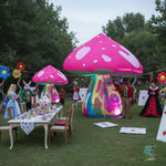 Trippy Creations giant pink fairy mushroom inflatable with white spots, a colorful psychedelic stem, and internal lighting. Set up for an Alice in Wonderland themed party.