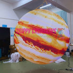 Trippy Creations giant inflatable Jupiter planet with swirling orange and white bands, ideal for space-themed events.