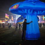 Trippy Creations giant blue inflatable mushroom props with yellow and pink accents, illuminated at night for an event.