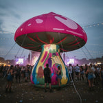 Trippy Creations giant inflatable mushroom prop, 3m-3.5m, with pink cap and psychedelic stem, illuminated for outdoor festival event.