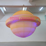 Trippy Creations giant inflatable Saturn planet with rings, illuminated with purple and orange lights, for space-themed events.