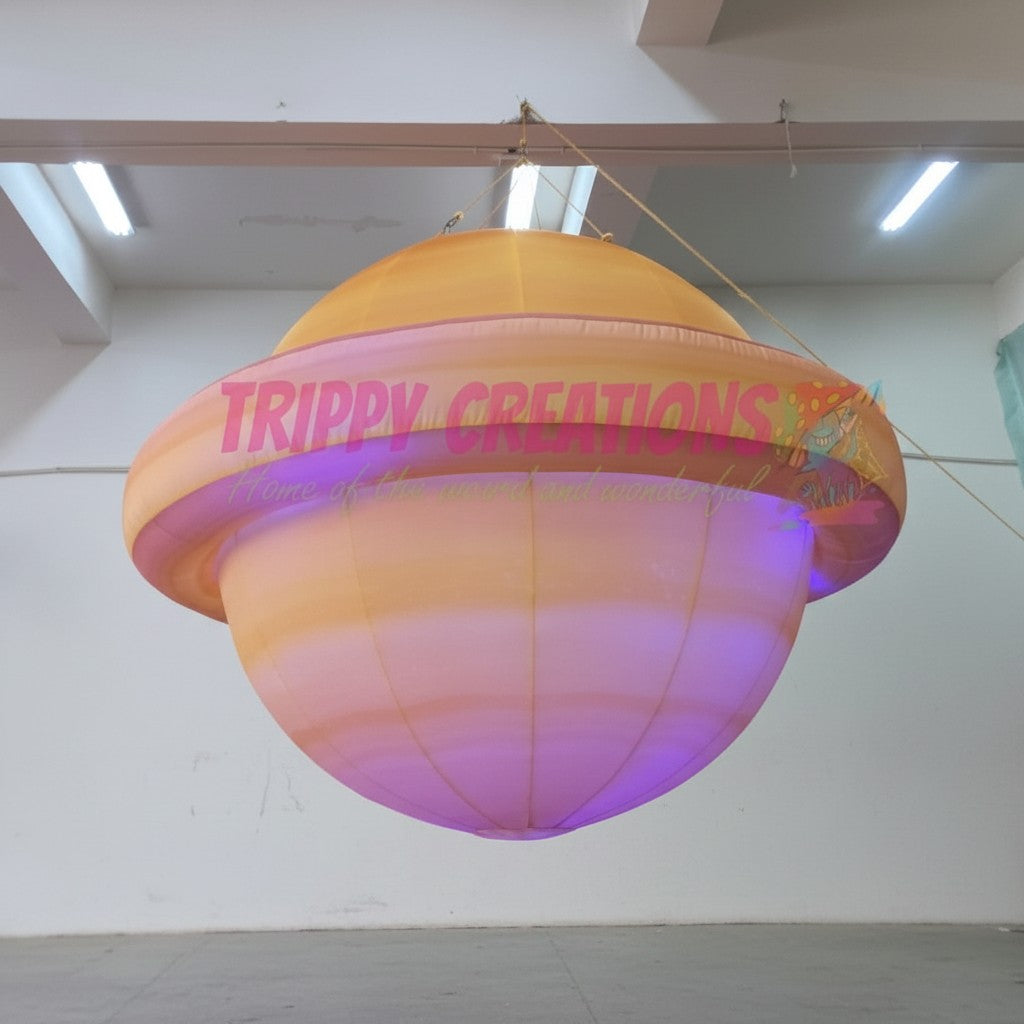 Trippy Creations giant inflatable Saturn planet with rings, illuminated with purple and orange lights, for space-themed events.