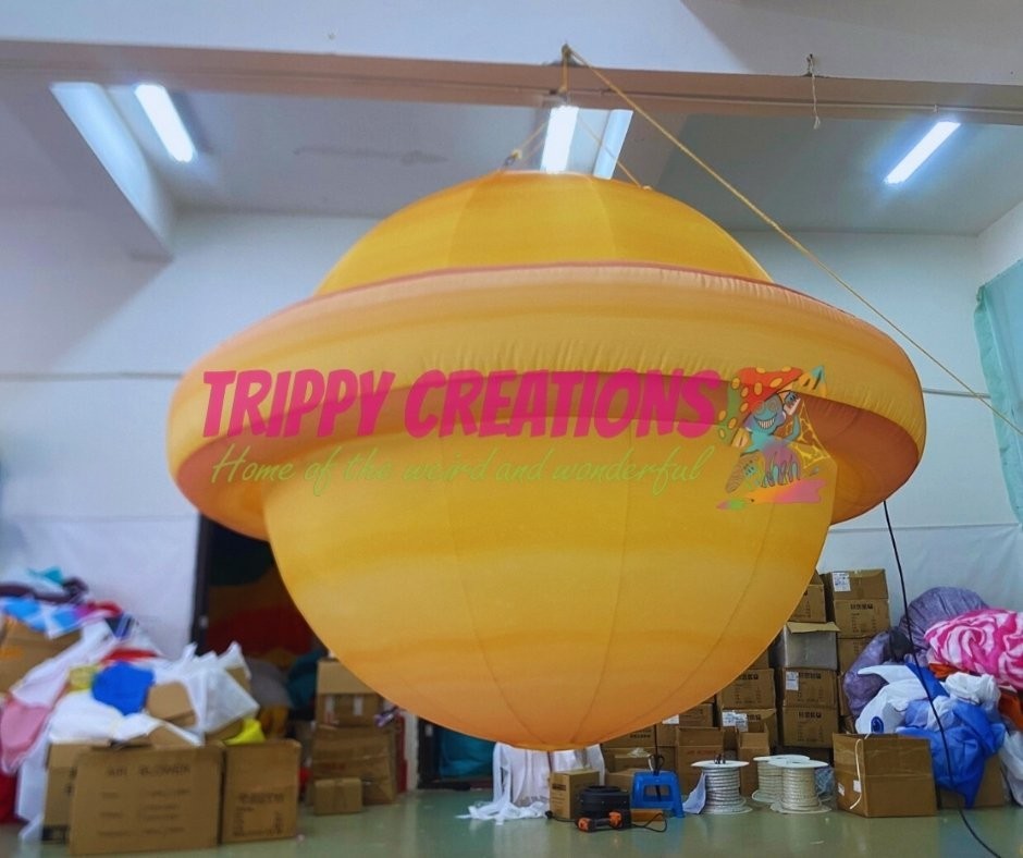 Trippy Creations giant inflatable Saturn planet with rings, yellow and orange, for space-themed events.