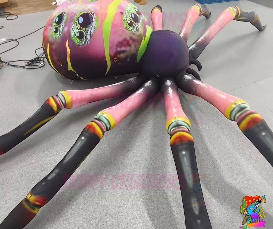 Trippy Creations giant inflatable spider decoration with pink legs and a purple body, featuring a colourful, multi-eyed head.