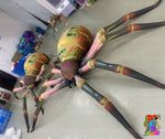 Trippy Creations giant inflatable Halloween spider with multiple eyes and segmented legs, orange, green, pink, and black.